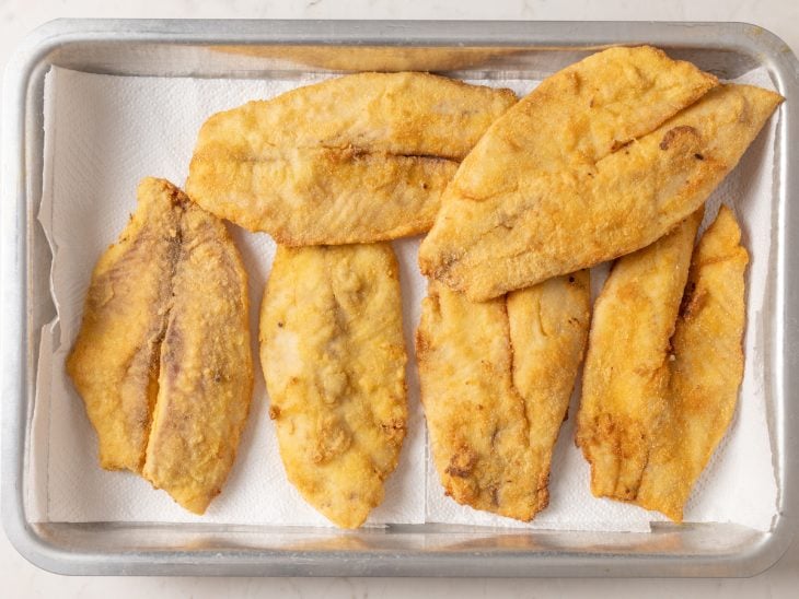 Filés fritos em uma assadeira forrada com papel-toalha.