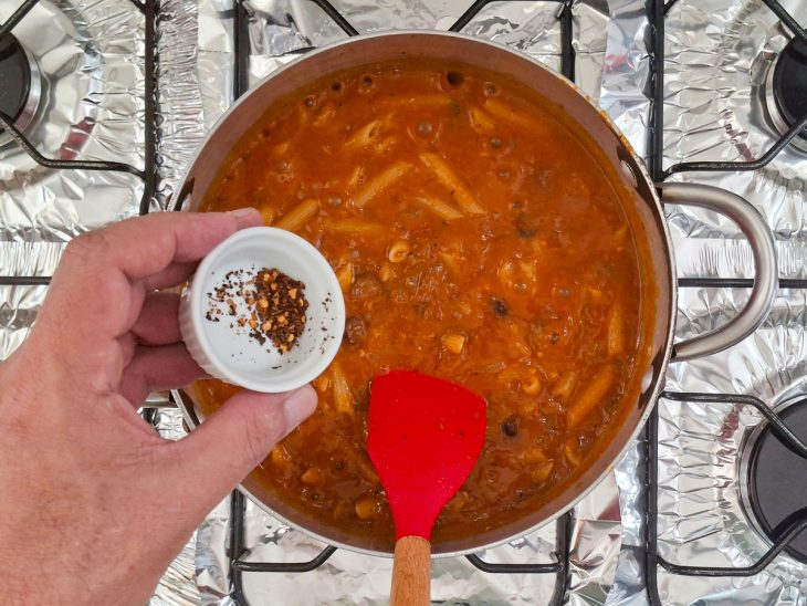 Penne cozinhando em água fervente com temperos.