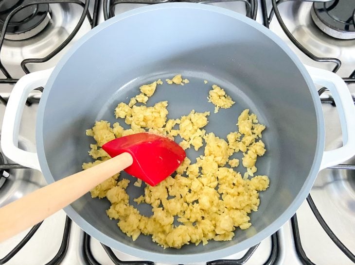 Uma panela, refogando cebola, manteiga e farinha.