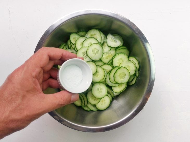 Um recipiente contendo pepino cortado em rodelas com sal.