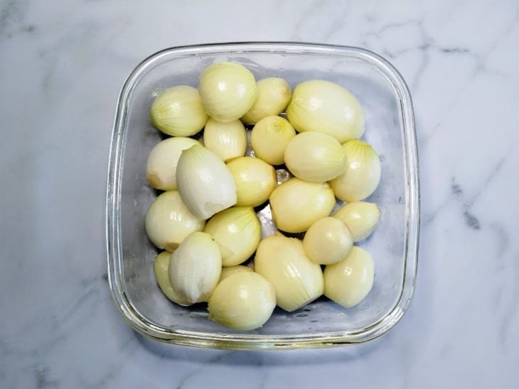 Um pote com minicebolas descascadas.
