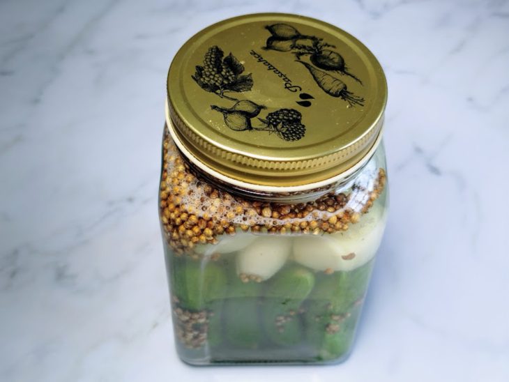 Um pote fechado contendo pepino em conserva com cebola.