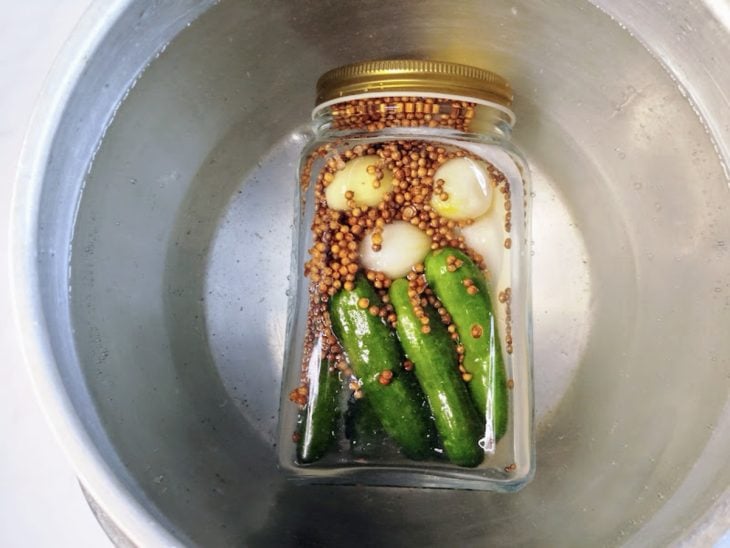 Um pote com a conserva dentro de uma panela com água.
