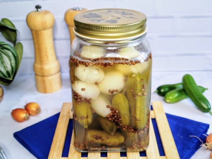 Um pote contendo pepino em conserva com cebola.