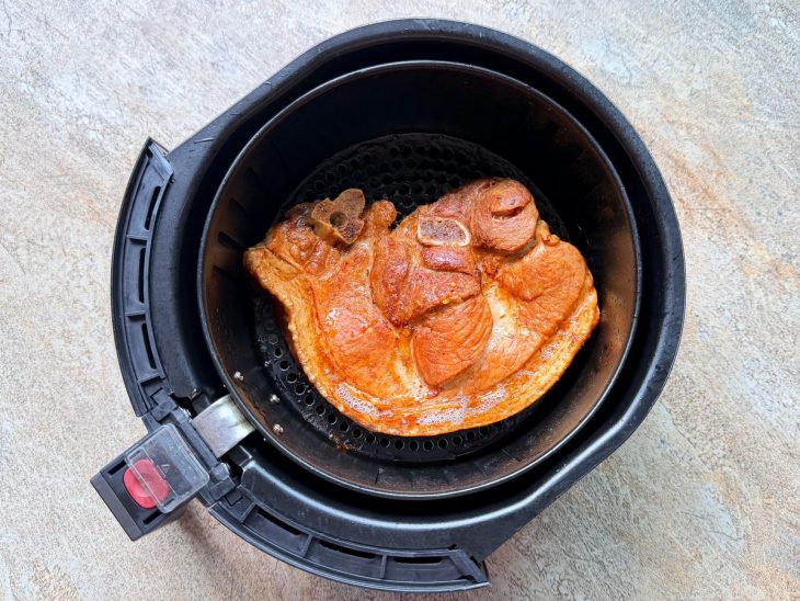 Pernil fora do saco, já dourando no cesto da airfryer.