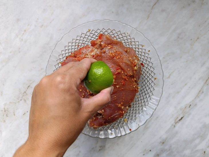 Colorau e suco de limão sendo espalhados sobre a carne.