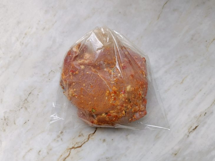 Pernil já temperado, embalado em saco plástico para marinar.