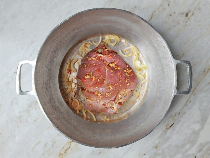 Pernil cozinhando na panela com água, absorvendo os sabores.