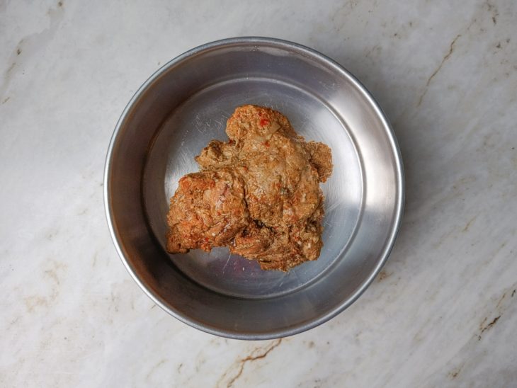 Pernil na assadeira, coberto com o molho do cozimento, pronto para ir ao forno.