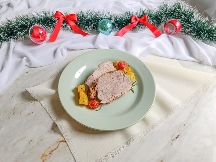 Pernil assado, bem dourado, servido com acompanhamentos no prato.