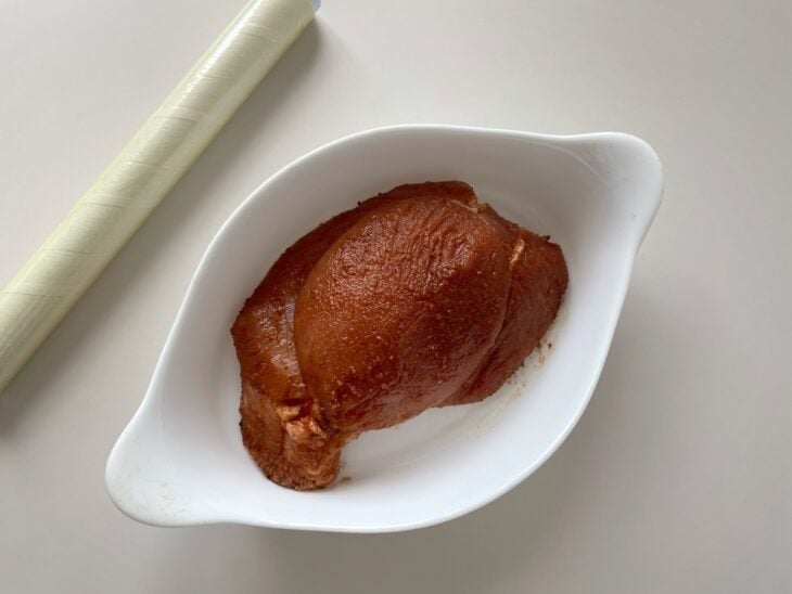 Recipiente com a carne temperada e coberto com plástico-filme sendo armazenado na geladeira.