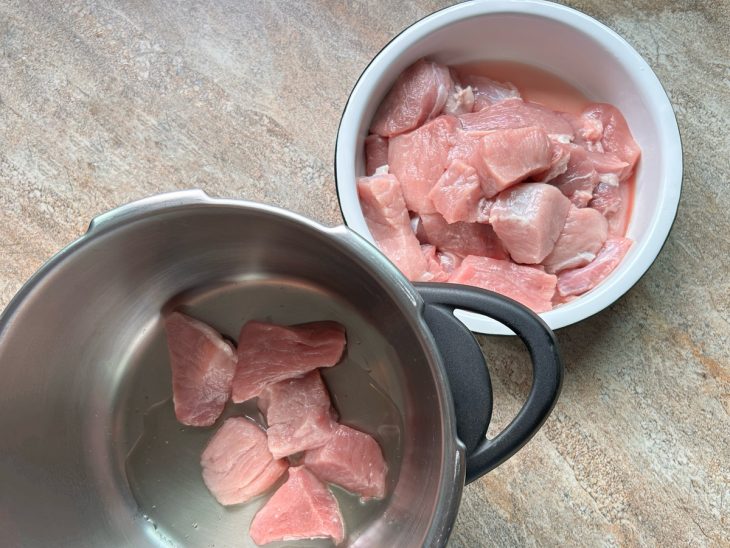 Cubos do pernil sendo transferidos para a panela.