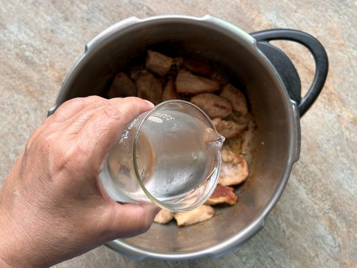 Cubos do pernil selados, água sendo adicionada aos poucos.