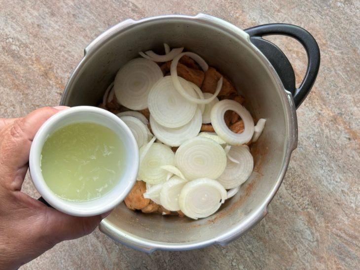 Rodelas de cebolas adicionadas na panela, suco do limão sendo colocado.