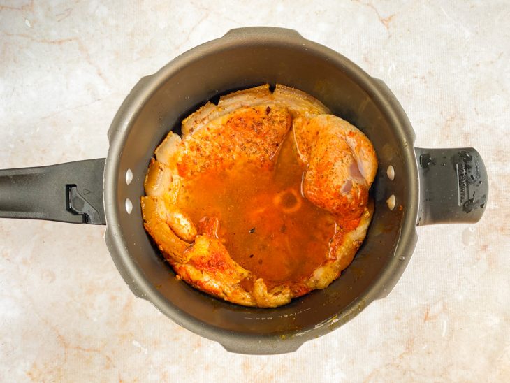 Pernil e água adicionado a panela de pressão com cebola.
