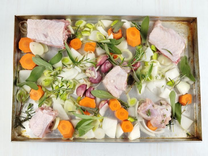 Miúdos e dorso junto ao vegetais na assadeira.