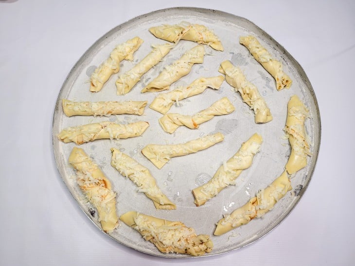 Uma forma redonda contendo vários petiscos de massa de pastel crus.