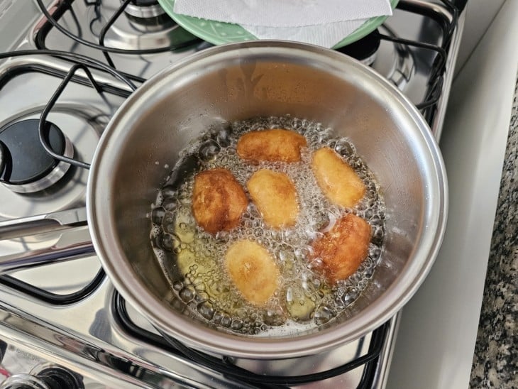 Os petiscos de salsicha sendo fritos por imersão na panela com óleo.