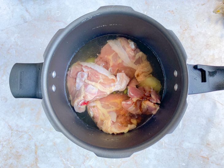 Uma panela de pressão com o frango a cozinhar com temperos.