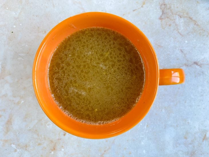 Um recipiente com o caldo de cozimento do frango.