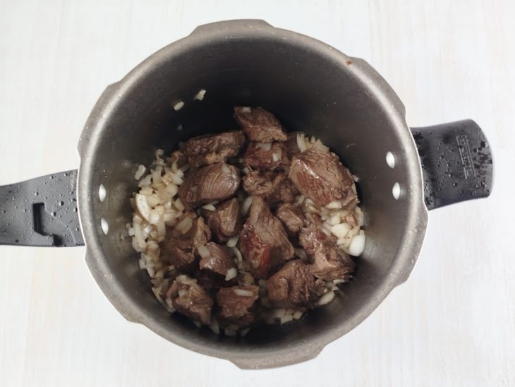 Cebola sendo refogada junto à carne dourada.