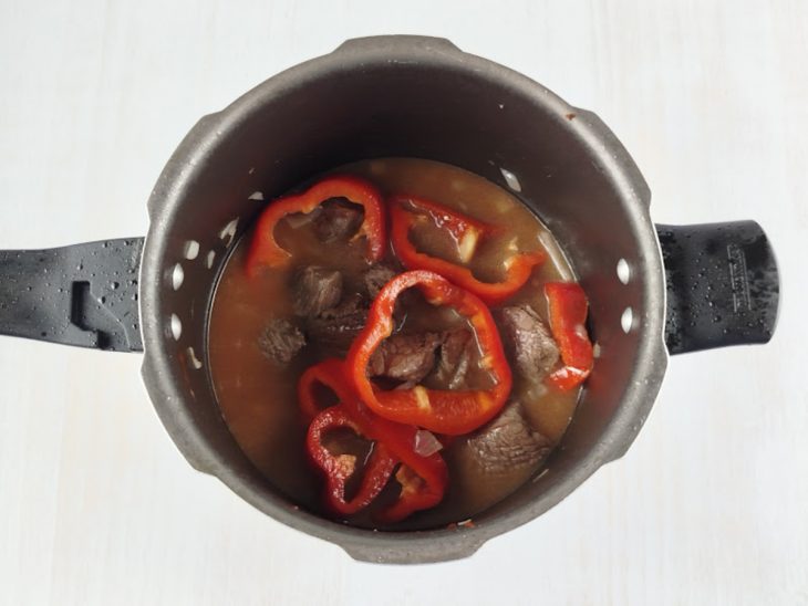 Alho e pimentão sendo adicionados para liberar aroma.