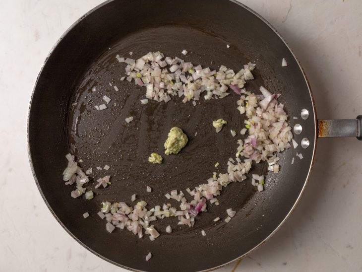 Panela com alho e cebola refogando em uma panela com óleo.
