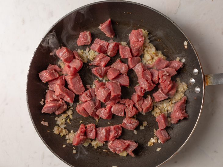 Carne selando na panela com alho e cebola.