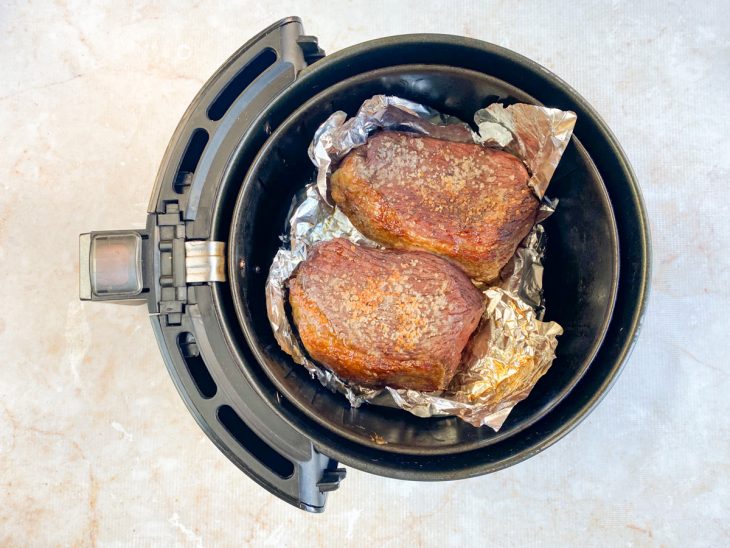 Bifes de picanha assados sobre o papel alumínio na air fryer.