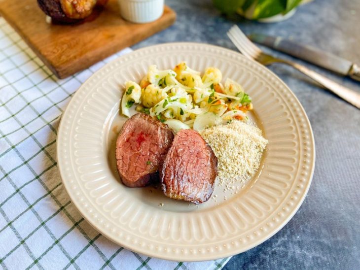 Fatias de picanha servidas com acompanhamentos num prato individual.