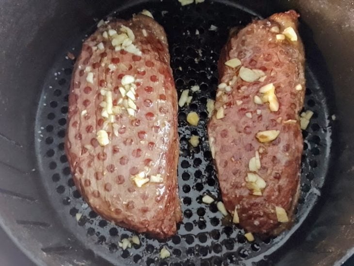 Bifes de picanha com manteiga de alho em um cesto de airfryer.