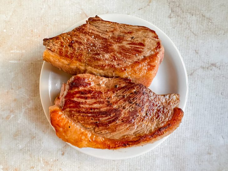 Carne dourada sendo virada para selar do outro lado.