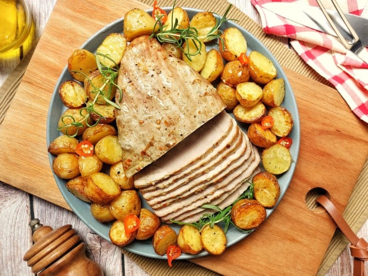 Um recipiente contendo picanha suína com batatas.