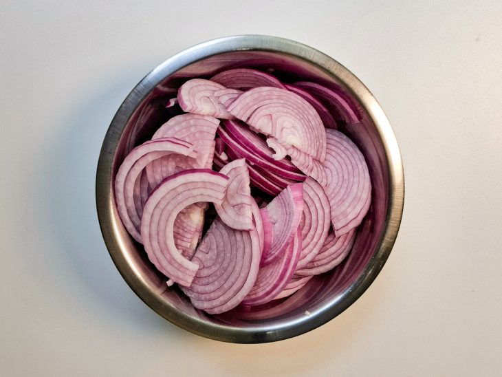 Numa tigela, as cebolas fatiadas.