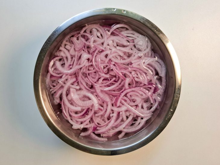 Em uma tigela com água geladas, as cebolas branqueadas.