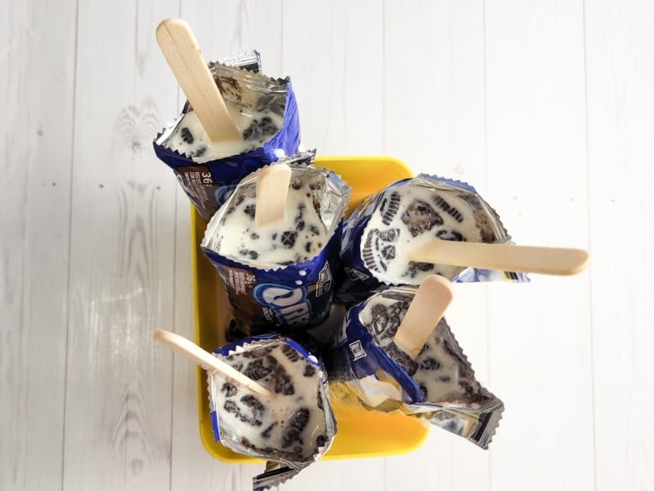 Um recipiente com vários pacotinhos Oreos abertos com creme de palito de sorvete.