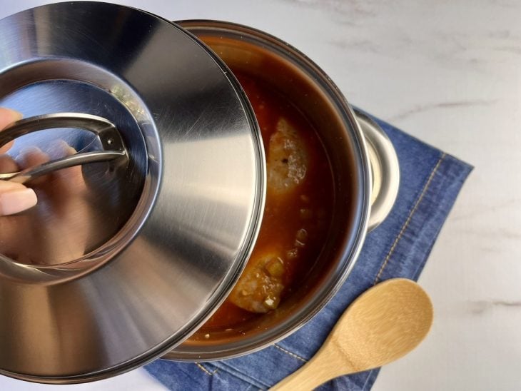 Uma panela cozinhando o pintado com molho.