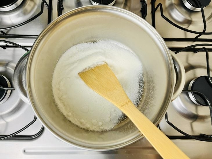 Uma panela com açúcar ao fogo.