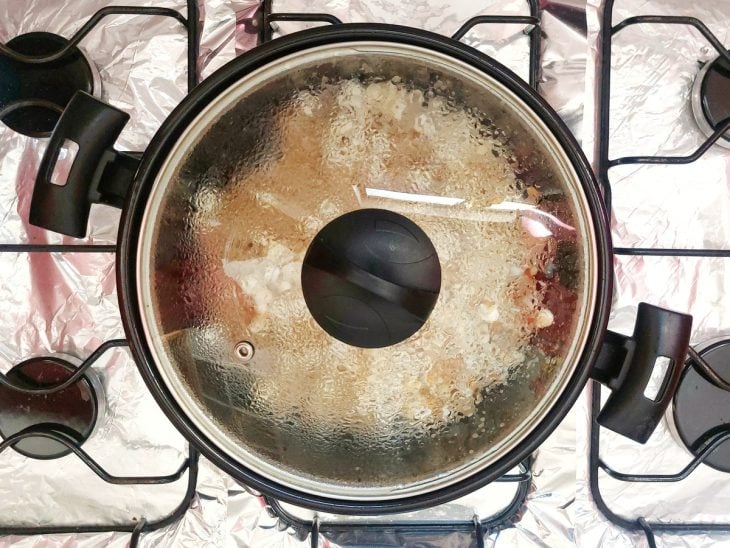 Uma panela tampada com a pipoca estourando.
