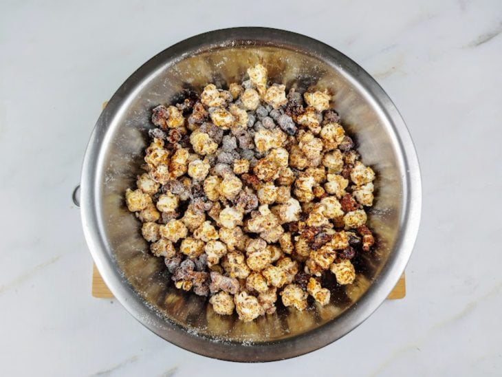 Pipocas caramelizadas polvilhadas com leite Ninho em um recipiente de alumínio.