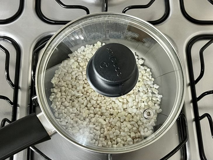 Uma panela tampada com pipoca de sagu ao fogo.