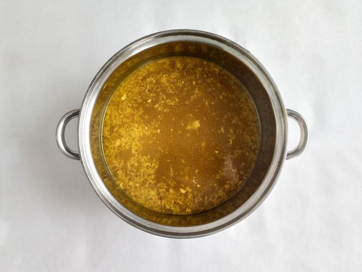Panela com alho, cebola e caldo de carne.