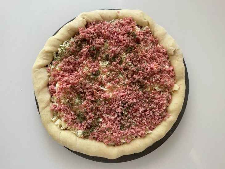 Mussarela e calabresa adicionadas na pizza.