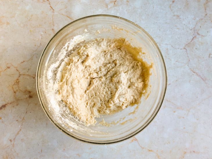 Em outra tigela, a mistura, o óleo, o sal e 2 xícaras da farinha formando uma massa.