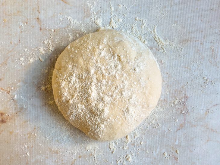 Na bancada, massa em formato de bola e enfarinhada.