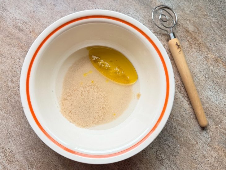 Na tigela, a água morna, o açúcar, o fermento e o azeite.