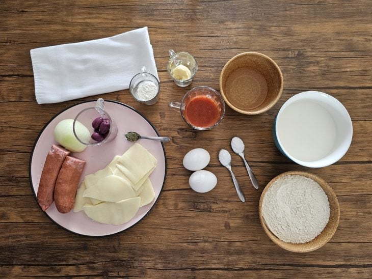 Ingredientes da pizza de calabresa fácil reunidos na bancada.