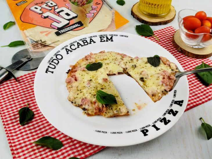 Pizza pronta para consumo com porção em destaque num garfo.