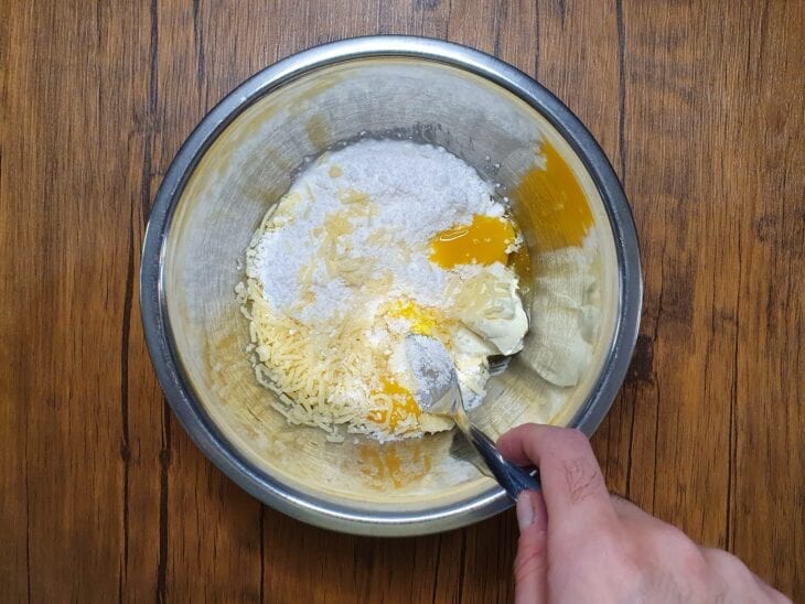Ovos, tapioca, queijo, requeijão e sal sendo misturados em uma tigela.