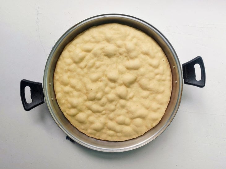 Uma forma com massa de pizza crua.